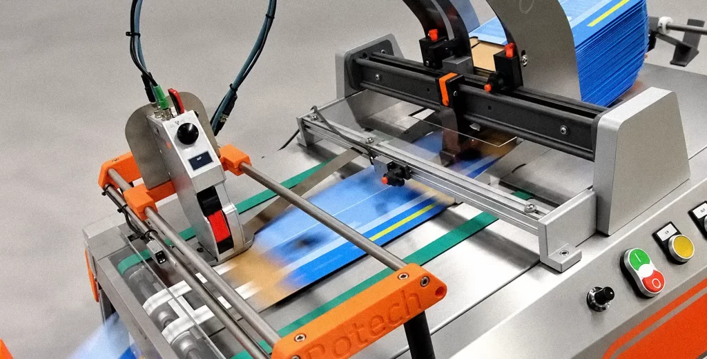 Industrial automated feeding system processing flat packaging materials on a conveyor for high-speed coding and printing.